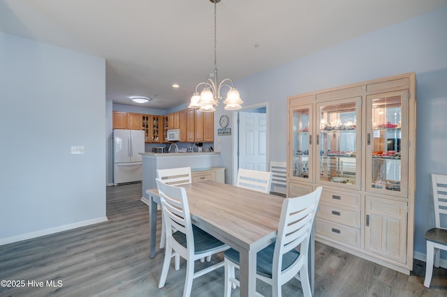 dining area with a chandelier, light wood-type flooring, and baseboards