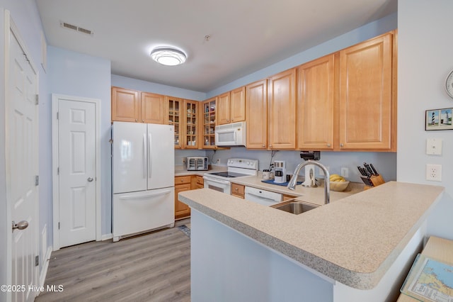 kitchen with white appliances, visible vents, a peninsula, light countertops, and a sink