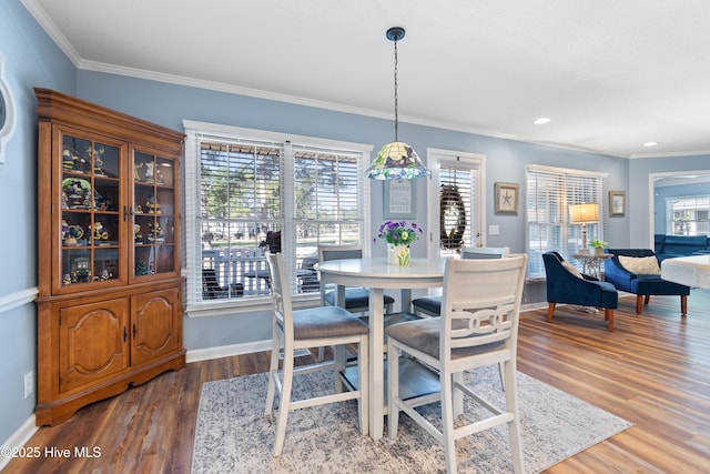 dining space featuring crown molding, baseboards, and wood finished floors