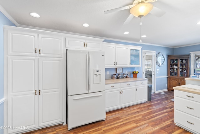 kitchen featuring white fridge with ice dispenser, light wood-type flooring, light countertops, and crown molding