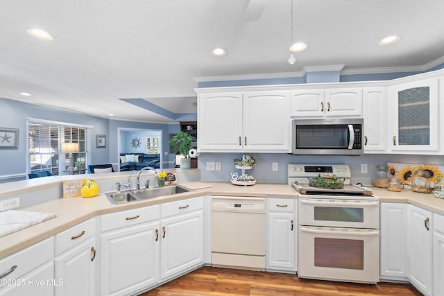 kitchen with light wood finished floors, light countertops, white cabinetry, a sink, and white appliances