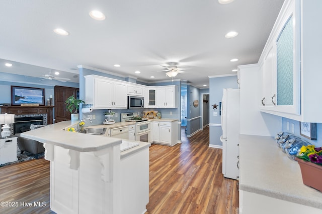 kitchen featuring stainless steel microwave, freestanding refrigerator, a sink, double oven range, and a peninsula