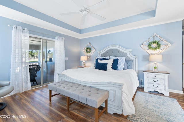 bedroom featuring access to exterior, a ceiling fan, a tray ceiling, and wood finished floors