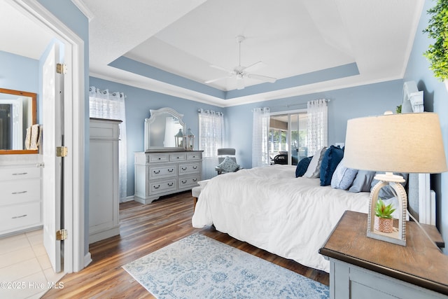 bedroom with crown molding, a tray ceiling, and wood finished floors