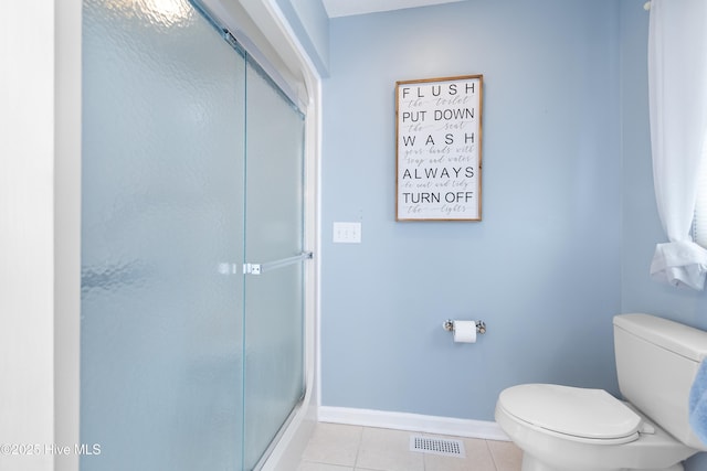 bathroom featuring baseboards, visible vents, toilet, a shower with shower door, and tile patterned floors