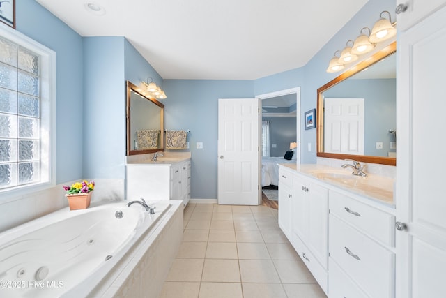 full bathroom featuring two vanities, a sink, tile patterned floors, a whirlpool tub, and ensuite bath