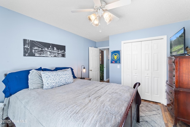 bedroom with ceiling fan, a closet, wood finished floors, and a textured ceiling