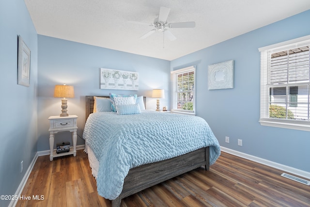 bedroom featuring baseboards, visible vents, ceiling fan, and wood finished floors