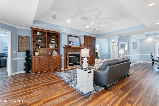 living room with a fireplace, a tray ceiling, and dark wood finished floors