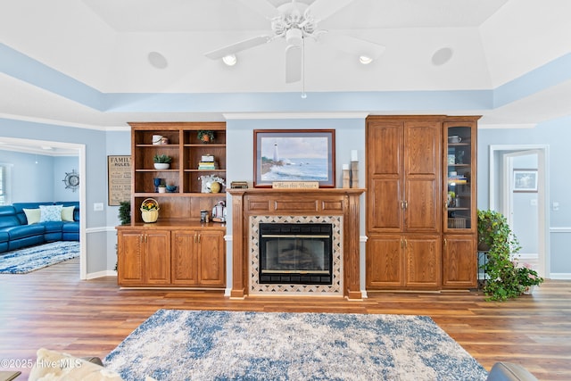 living room featuring light wood-style floors, a glass covered fireplace, and a raised ceiling