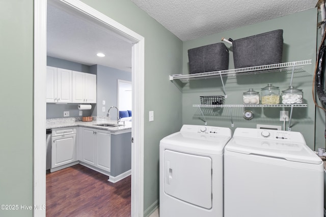 laundry area with a textured ceiling, laundry area, a sink, dark wood-style floors, and washer and clothes dryer