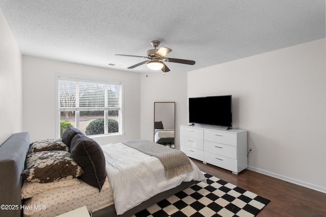 bedroom with visible vents, dark wood-type flooring, a ceiling fan, a textured ceiling, and baseboards