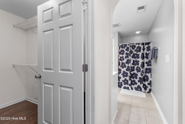 bathroom featuring baseboards, visible vents, curtained shower, tile patterned flooring, and a textured ceiling