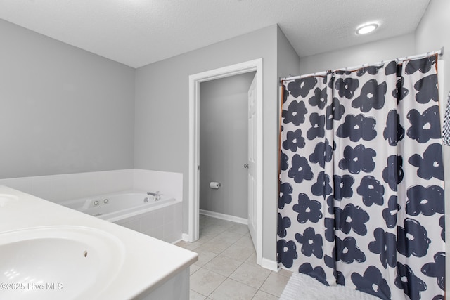 bathroom with a garden tub, a sink, a textured ceiling, baseboards, and tile patterned floors