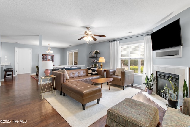 living room with visible vents, a textured ceiling, wood finished floors, a tile fireplace, and baseboards