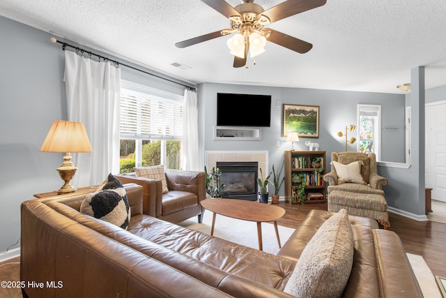 living room with a textured ceiling, a fireplace, visible vents, and wood finished floors