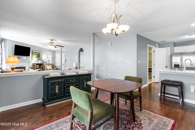 dining area featuring dark wood-style floors, arched walkways, visible vents, a textured ceiling, and baseboards