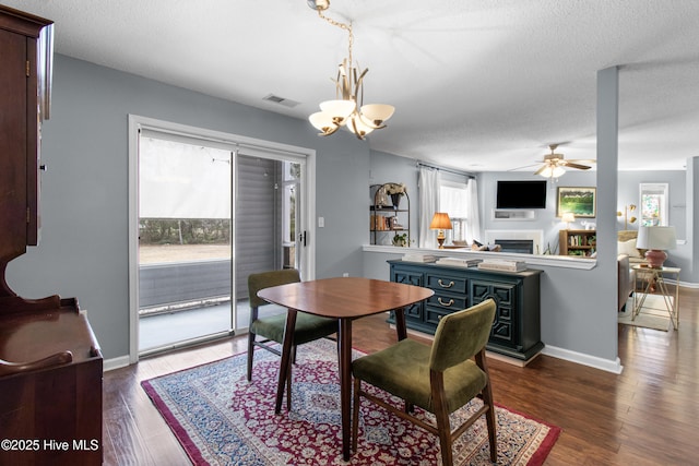 dining space featuring baseboards, visible vents, dark wood-type flooring, a textured ceiling, and a fireplace