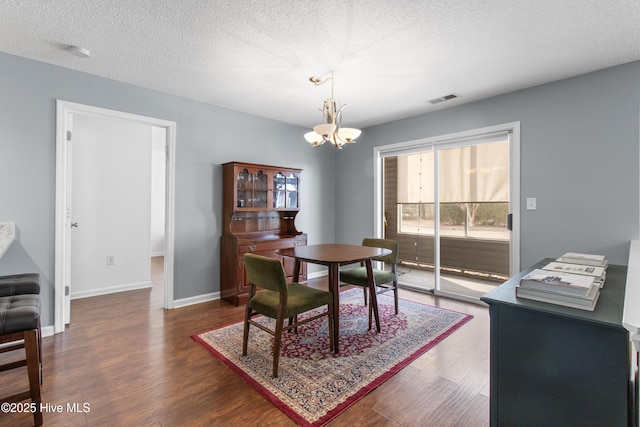 dining area with a chandelier, dark wood-style flooring, visible vents, and baseboards