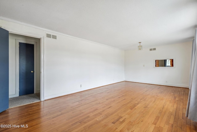 spare room featuring visible vents, a textured ceiling, crown molding, and light wood-style floors