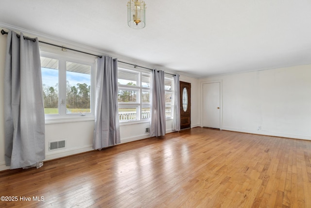 interior space featuring light wood-type flooring, visible vents, and baseboards