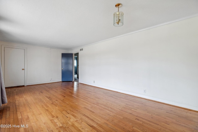 spare room with visible vents, baseboards, crown molding, and light wood finished floors