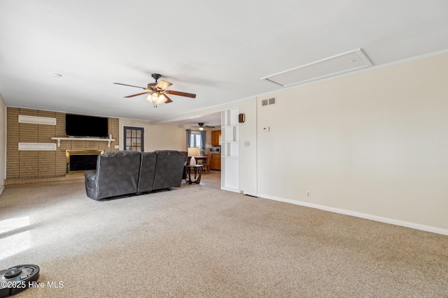 unfurnished living room featuring visible vents, a brick fireplace, baseboards, attic access, and carpet floors