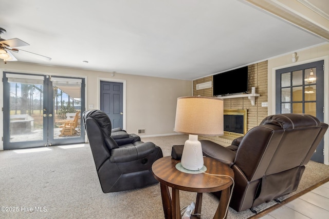 living area featuring visible vents, a ceiling fan, french doors, a fireplace, and light colored carpet