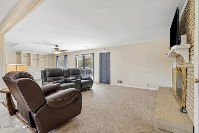 living area with a ceiling fan, visible vents, baseboards, a fireplace, and light colored carpet