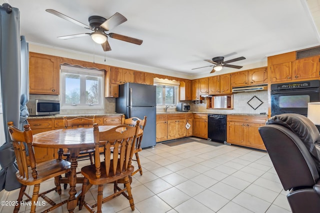 kitchen with decorative backsplash, black appliances, a wealth of natural light, and under cabinet range hood