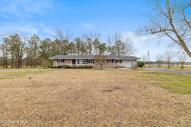 view of front facade with a front lawn, a porch, a garage, and driveway