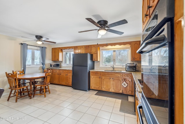 kitchen featuring plenty of natural light, brown cabinets, black appliances, and a sink