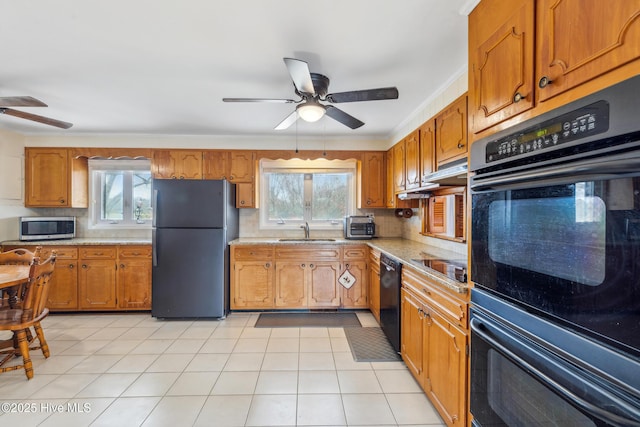 kitchen with black appliances, brown cabinetry, a wealth of natural light, and a sink