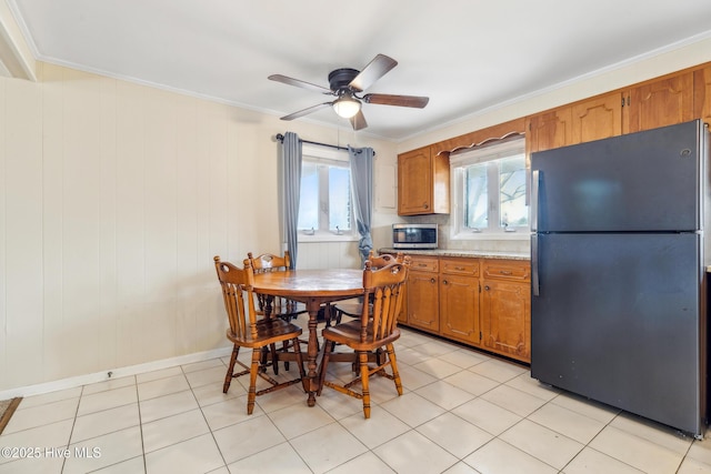 dining space with light tile patterned floors, plenty of natural light, a ceiling fan, and ornamental molding