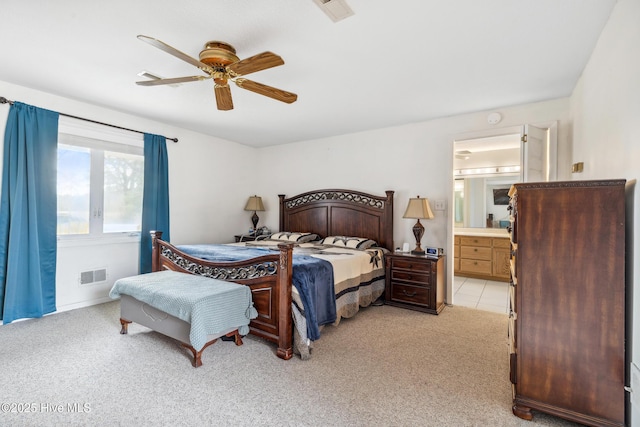 bedroom featuring a ceiling fan, light colored carpet, visible vents, and connected bathroom