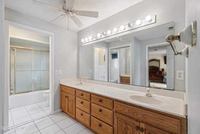 ensuite bathroom featuring tile patterned flooring, double vanity, toilet, and a sink