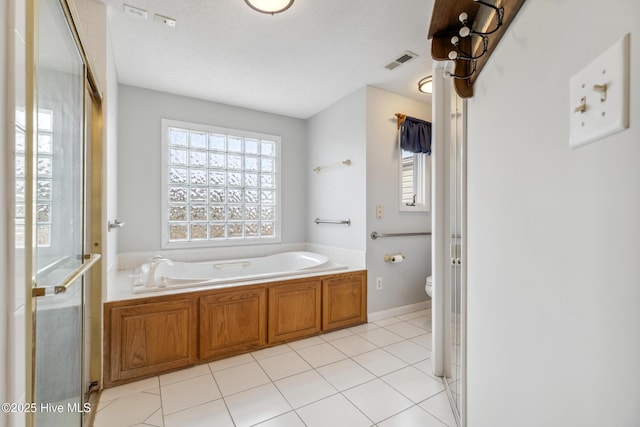 full bath with visible vents, toilet, a garden tub, tile patterned floors, and a textured ceiling