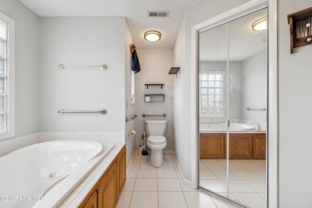 full bathroom with visible vents, a jetted tub, baseboards, toilet, and tile patterned floors