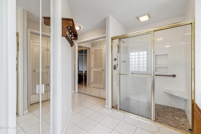 full bath featuring a closet, a shower stall, and tile patterned flooring