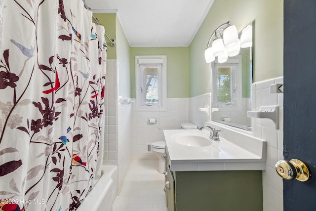 bathroom with toilet, vanity, ornamental molding, wainscoting, and tile walls