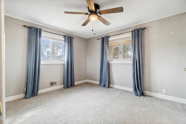 empty room with visible vents, ceiling fan, baseboards, ornamental molding, and carpet floors