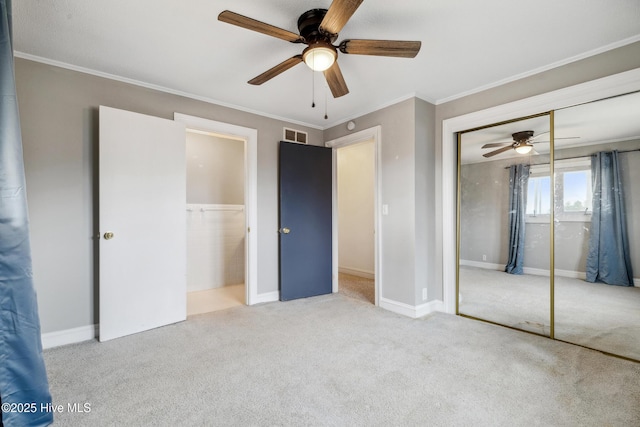 unfurnished bedroom featuring visible vents, a closet, carpet floors, crown molding, and baseboards