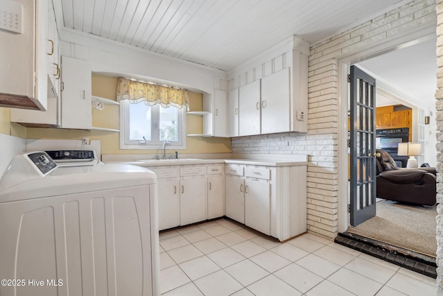 kitchen featuring washing machine and clothes dryer, open shelves, a sink, light countertops, and white cabinetry