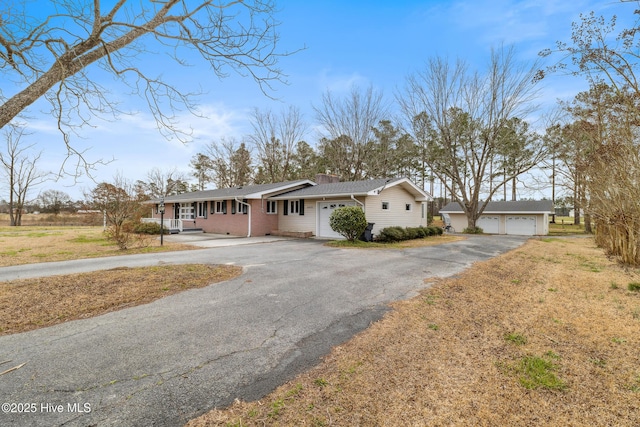 single story home with brick siding, a garage, and a chimney