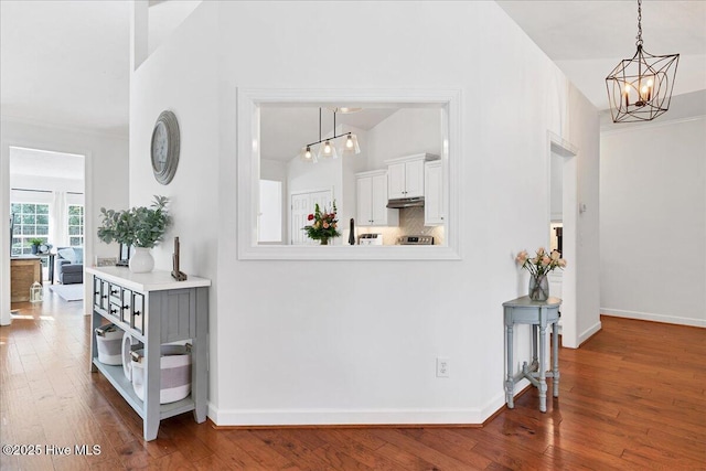 hall with a chandelier, baseboards, and hardwood / wood-style floors