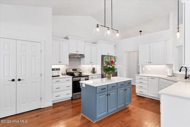 kitchen with under cabinet range hood, white cabinets, appliances with stainless steel finishes, and blue cabinets