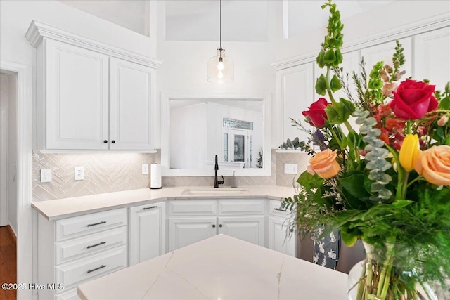 kitchen with backsplash, white cabinetry, and a sink