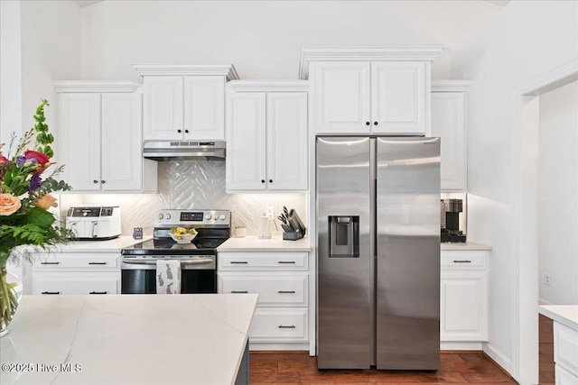 kitchen with stainless steel appliances, light countertops, under cabinet range hood, white cabinetry, and tasteful backsplash