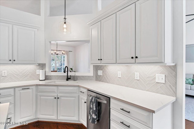 kitchen with a sink, decorative backsplash, white cabinets, pendant lighting, and dishwasher