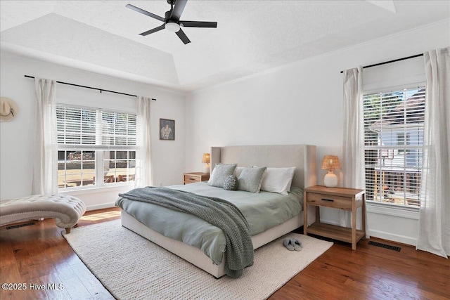 bedroom with visible vents, baseboards, hardwood / wood-style floors, a textured ceiling, and a raised ceiling